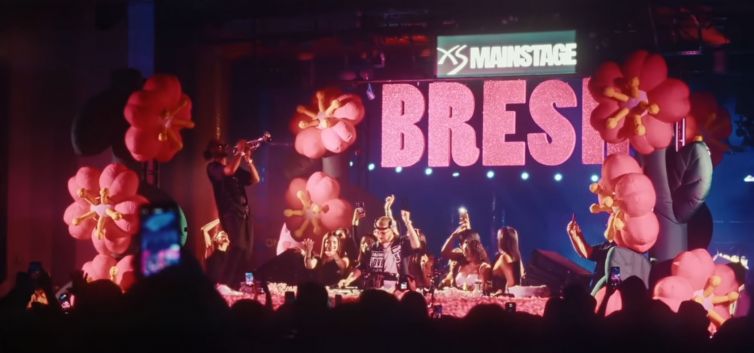 HUGEL performing live to a high-energy crowd with percussionists and brass players.