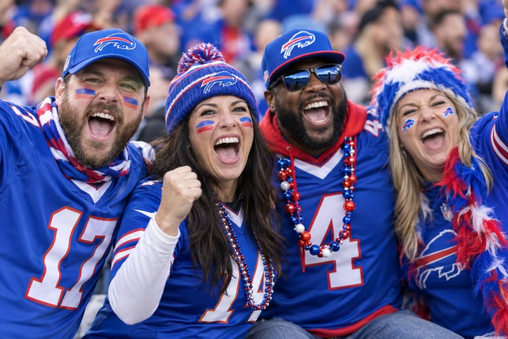 Buffalo Bills fans in blue red and white gear cheering together in the stands