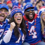Buffalo Bills fans in blue red and white gear cheering together in the stands