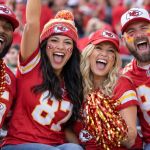Kansas City Chiefs fans in red and gold gear cheering together in the stands